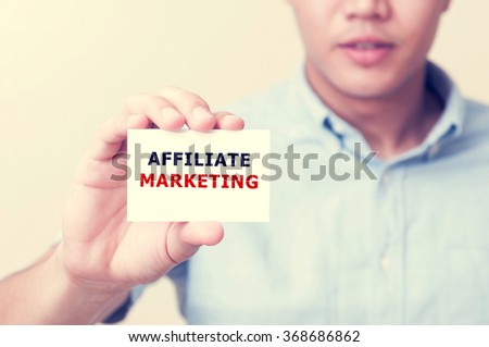 Man's hand showing AFFILATE MARKETING text on the card business card - closeup shot on white background.