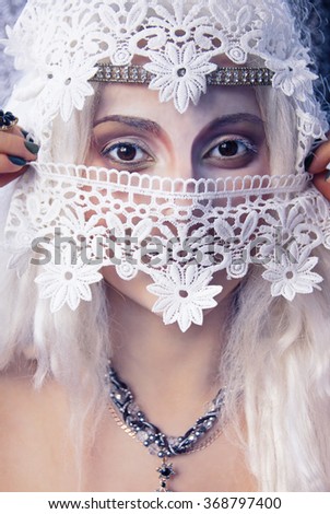 The girl with big brown eyes in a white wig and many accessories posing for a portrait.