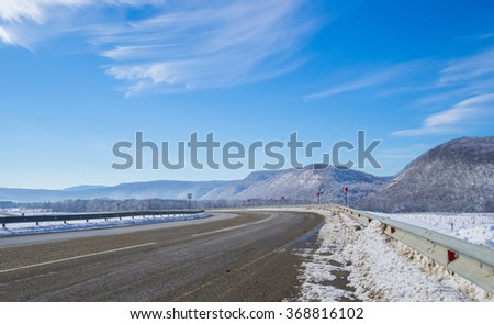 Winter road to the mountain. Turn, rise. Road sign turn