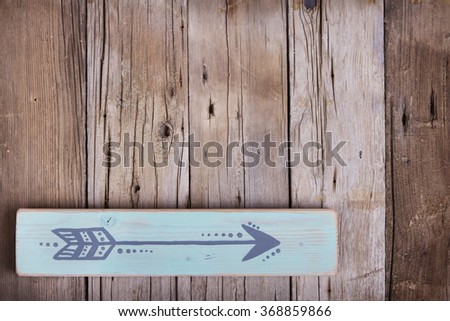 One hand painted arrow on a wooden plank on a rough wooden background