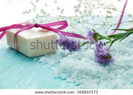 natural organic soap, and sea salt with flowers on a blue wooden table