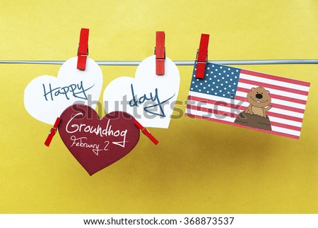 White hearts - cute face groundhog and text Happy Groundhog Day 2016 February 2. USA flag hanging on colorful pegs ( clothespin ) on a line against yellow background. 