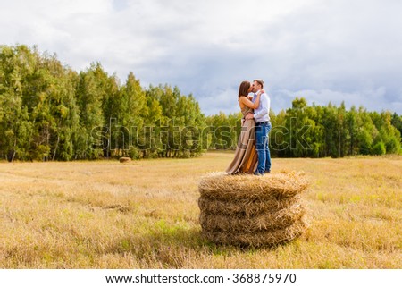 Couple in love young people resting on the haystack autumn evening