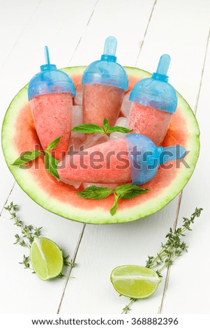Watermelon popsicles with mint and lime on white wooden background