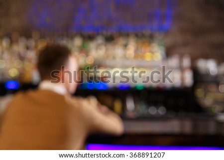 Blured picture with man sitting at the bar or pub