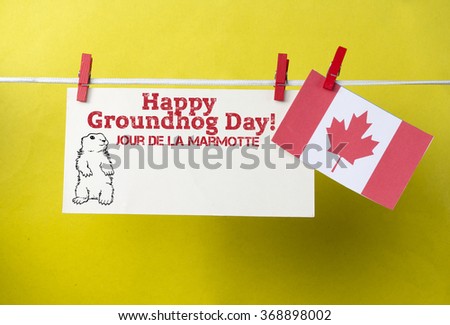 White envelope, cute face groundhog and text Happy Groundhog Day.with Canada flag hanging on colorful pegs  clothespin. Jour de la Marmotte - Groundhog Day Canadian on French. Toned image
