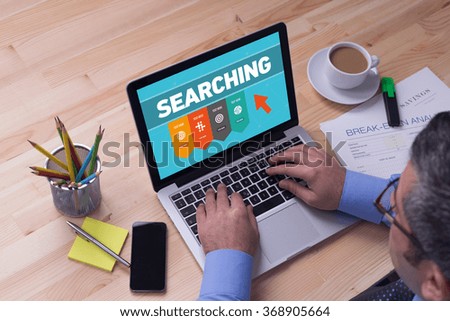 Man working on laptop with SEARCHING on a screen