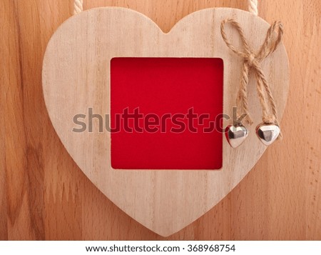 Wooden picture frame with love heart on wooden background.