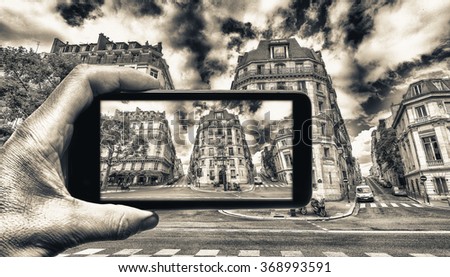 Taking colors out of black and white. Female hand with smartphone taking a picture of Paris. Tourism concept.