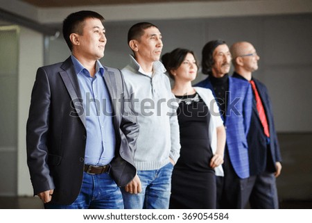Business team five people, a man and woman looking into the distance, all are behind their leader descending inside an office building. Team building, network marketing. Selective focus, shallow dof.