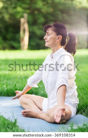 Middle aged woman doing yoga early in the morning in a park