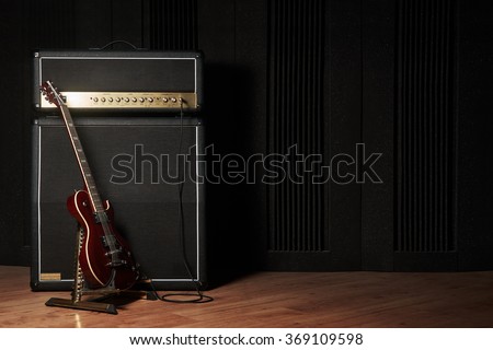 Red electric guitar and classic amplifier on a dark background                         Royalty-Free Stock Photo #369109598
