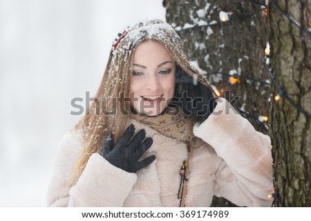 Young woman talking by the phone during the snowfall
