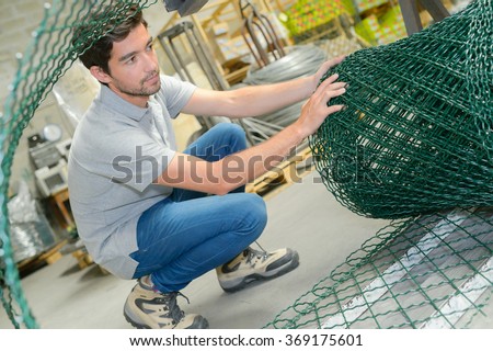 Man unrolling fencing wire Royalty-Free Stock Photo #369175601