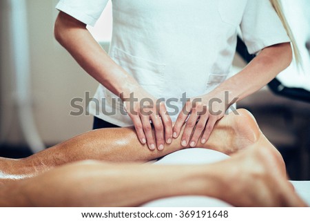 Sports Massage. Massage therapist working with patient, massaging his calves. Toned image. Royalty-Free Stock Photo #369191648