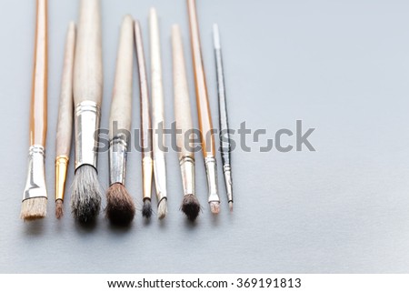 Used, vintage paintbrushes on gray background. macro view different size wooden and textured paint brush, shallow depth of field photography. copy space