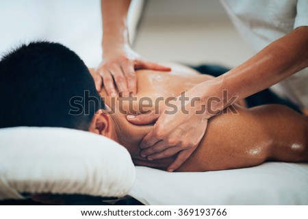 Sports massage. Massage therapist massaging shoulders of a male athlete, working with Trapezius muscle. Toned image Royalty-Free Stock Photo #369193766
