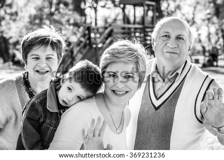 Family wave! Grandmother, grandfather, mother and grandson in autumn in a park. Black and white photography