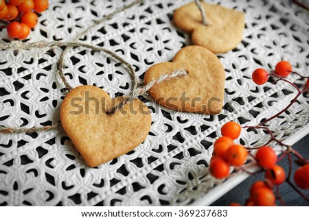 Heart shaped biscuits with ash berries and thread on a white tray