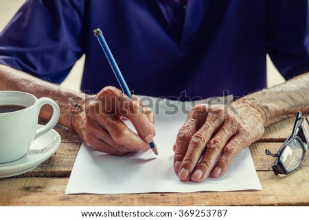 old man writing with a pencil in a notebook,Handwriting. vintage effect