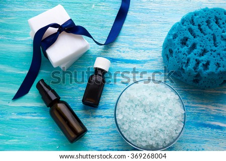 natural organic soap bottles essential oil and sea salt herbal bath  on a blue wooden table foam sponges 