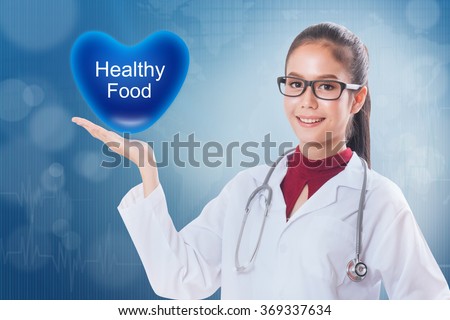 Female doctor holding heart with Healthy Food sign on medical background.