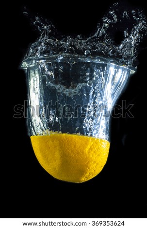 fresh lemon falling into water isolated on black background