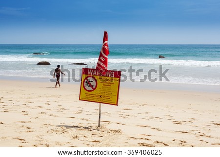 Warning sign on the beach swimming prohibited is disregarded by a man