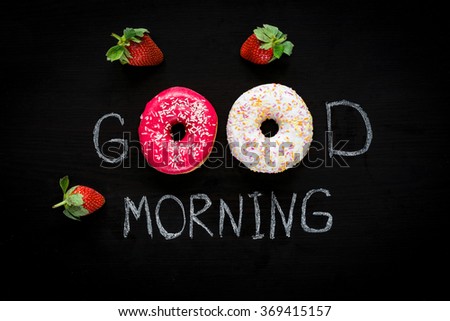Donuts and strawberries. Good morning greeting written on black chalk board. Table top view. Breakfast food concept, Valentines day food. Flat lay