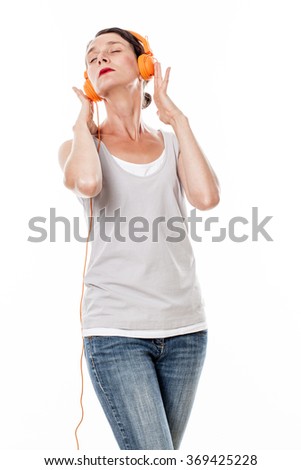 fashionable sound concept - concentrated 30s female musician listening to music on orange headphones, white background studio