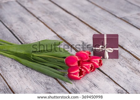 pink tulips and a gift with a bow on a white gray wooden background