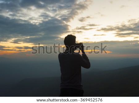 Silhouette of a man taking pictures of sunset.