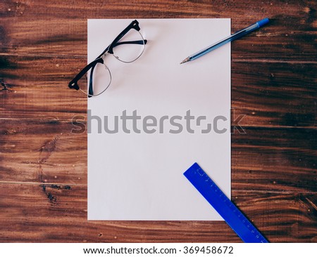 Empty white paper,glasses, pen and ruler on the wood table