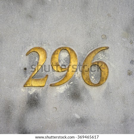 brass house number two hundred and ninety six on a stone wall.