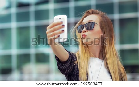 Young happy girl make a selfie with his smartphone, outdoors