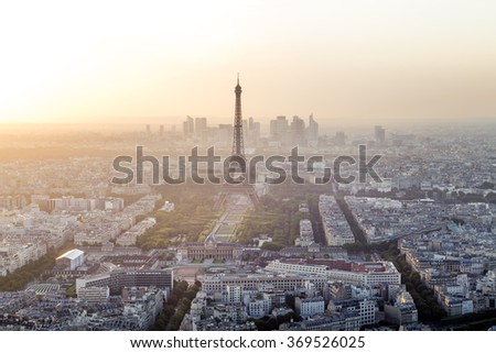 Skyline of Paris, France and Eiffel Tower with houses, streets and parks and with warm, colorful sunset light with business district La Defense in the background