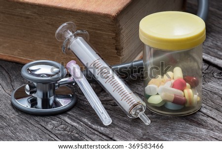 still life photography : syringe, bottle of medicine, stethoscope and old textbook on old wood
