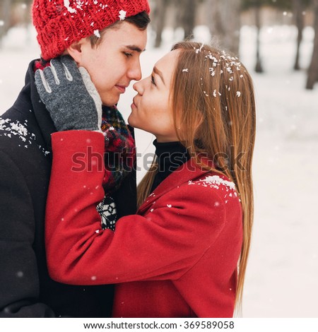 Close up winter portrait of young couple in love  hugging , wearing stylish  warm  coat, knitted hat and gloves . Soft toned photo. Romantic mood. Holidays concept.