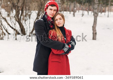 Close up winter portrait of young couple in love  hugging , wearing stylish  warm  coat, knitted hat and gloves . Soft toned photo. Romantic mood. Holidays concept.