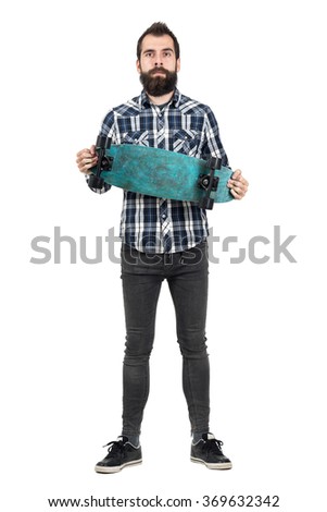 Proud hipster holding long board looking at camera. Full body length portrait isolated over white studio background. 