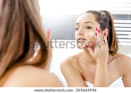 Attractive girl putting anti-aging cream on her face Royalty-Free Stock Photo #369664946