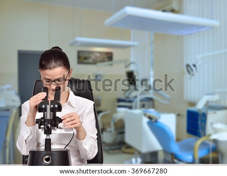 Woman scientist looking through microscope in laboratory