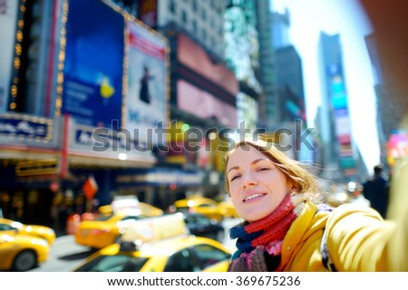 Beautiful young woman taking a selfie with her smartphone on Times Square, New York