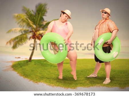 Obese couple in swimsuit with green lifebuoy. Holidays on the beach.Funny people sending greeting from tropical paradise. Warm filtered picture.