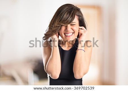 Young pretty woman covering her ears on unfocused background