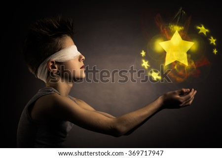 Glowing Yellow Stars Over the Open Hands of a Blind Boy with Bandage on his Eyes Against Gray Background. Royalty-Free Stock Photo #369717947