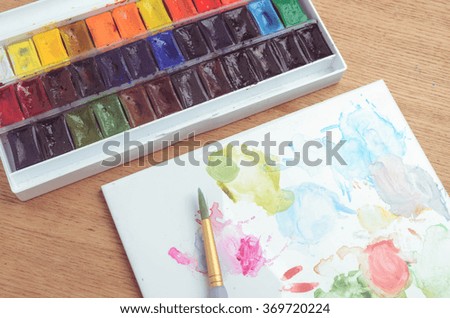Watercolor half-pan paints  palette  set on wooden background