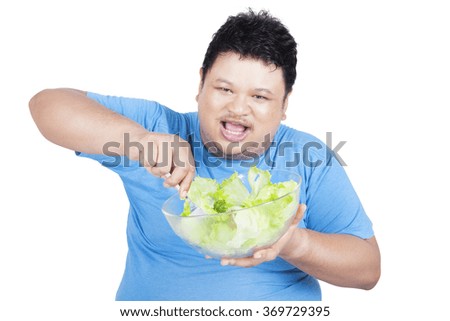 Picture of cheerful overweight person eating a bowl of salad for weight loss, isolated on white background