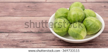 Brussels sprout in white bowl over wooden background