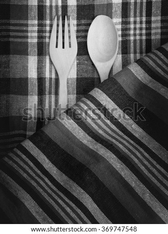 Spoon and fork on tablecloth, black and white.